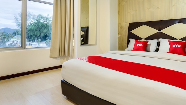 A hotel room with a large window, a bed with a red and white bedspread, and a patterned wall. - OYO 89583 Grove Hotel (Kajang)