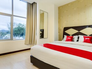 A hotel room with a large window, a bed with a red and white bedspread, and a patterned wall.