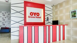 A hotel reception desk with a prominent "OYO Grove Hotel" sign, a patterned wall, and a tiled floor. - OYO 89583 Grove Hotel (Kajang)