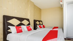 Ein Hotelzimmer mit einem Bett, zwei Nachttischen, einer Wandklimaanlage und einer Tür.