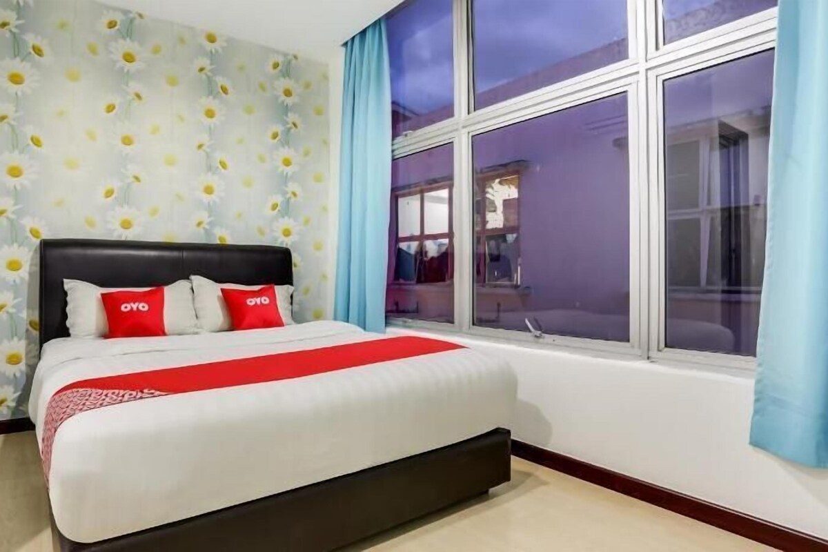 Een slaapkamer met een bed, een raam met gordijnen en een muur met een margriet patroon.