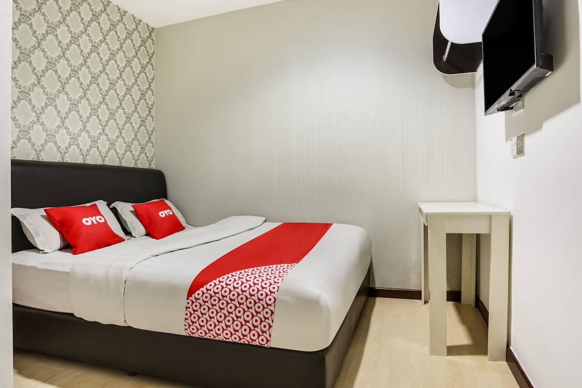 A modern hotel room with a bed, a small bedside table, and a TV mounted on the wall.