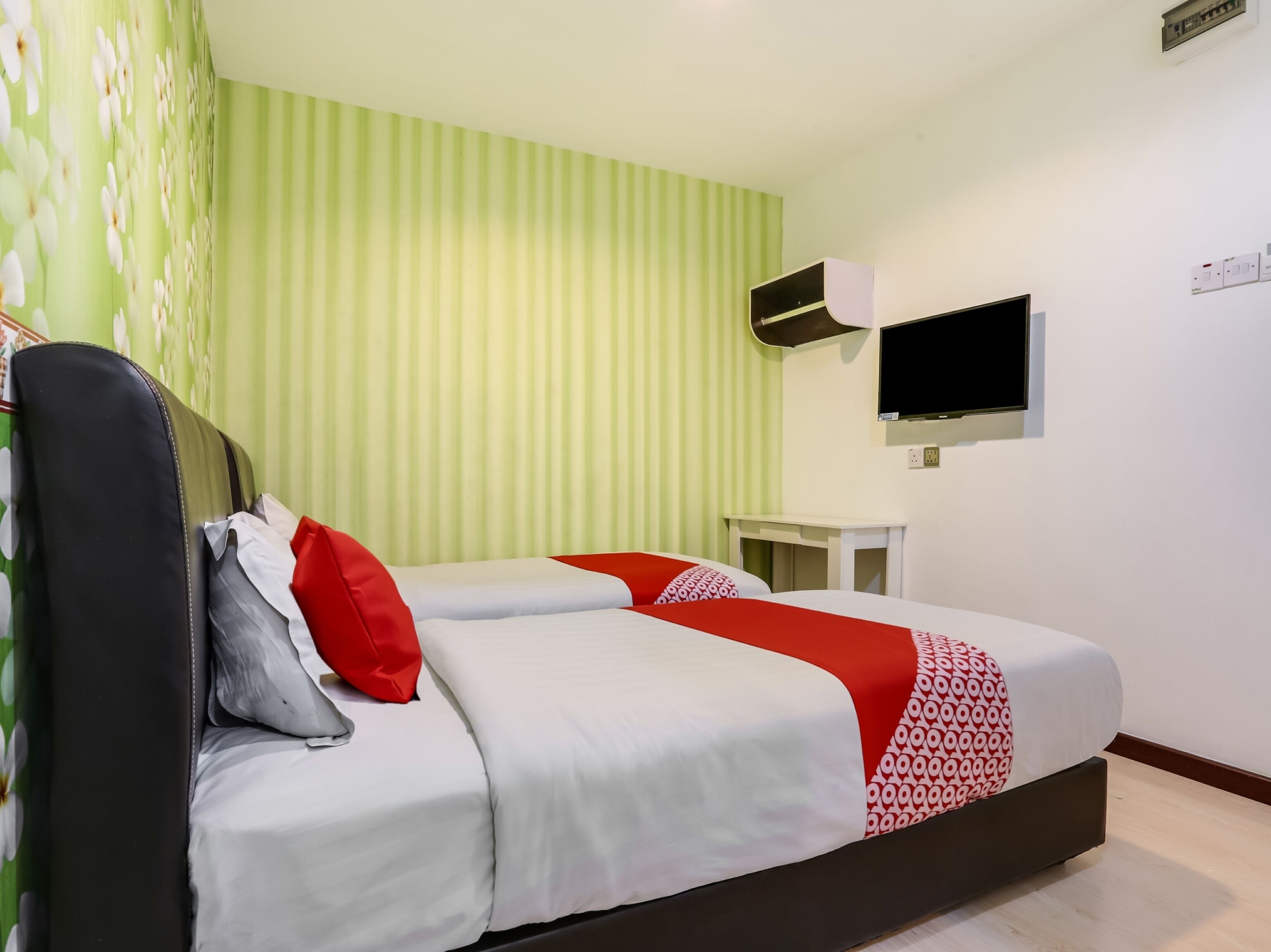 Ein Hotelzimmer mit einem Bett, einem an der Wand montierten Fernseher und einem kleinen Tisch.