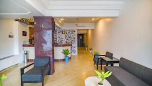 Un vestíbulo de hotel con una recepción, zona de estar y un pasillo que conduce a otras habitaciones.