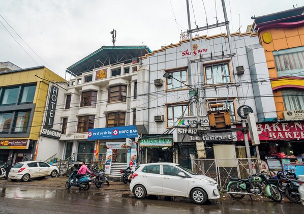 Un edificio de varios pisos con un letrero que indica 'Shagun Hotel' y 'HDFC Bank' en la planta baja.