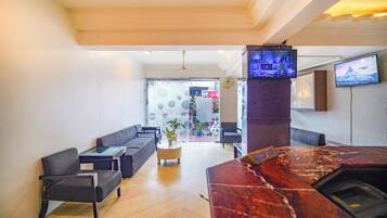 Un vestíbulo moderno con una recepción de mármol, sofás y una televisión.