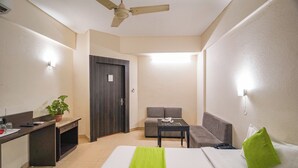 Una habitación de hotel con cama, escritorio, sofá, mesa y ventilador de techo.