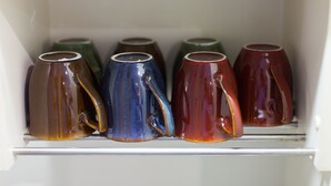 A white cabinet with six ceramic mugs in various colors. - Sakamoto Building 7F (Osaka)