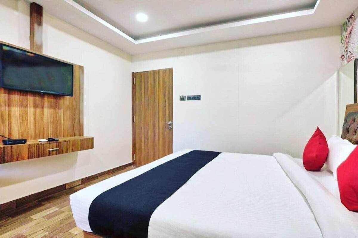 Une chambre d’hôtel avec un lit, un téléviseur fixé sur un panneau en bois, une armoire et une porte.