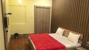 Ein Hotelzimmer mit Bett, Nachttisch, Kleiderschrank und einem kleinen Mülleimer.
