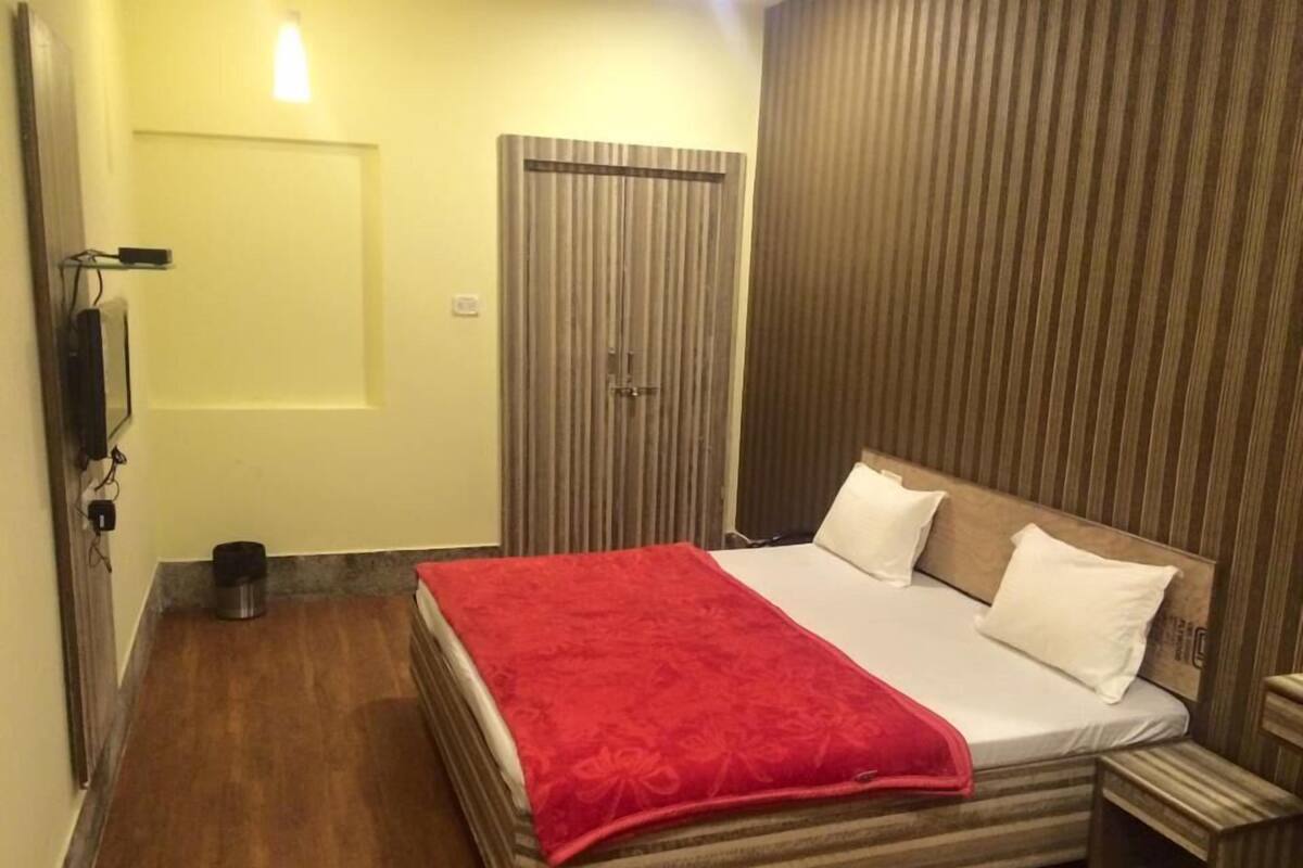 A hotel room with a bed, a bedside table, a wardrobe, and a small trash bin.