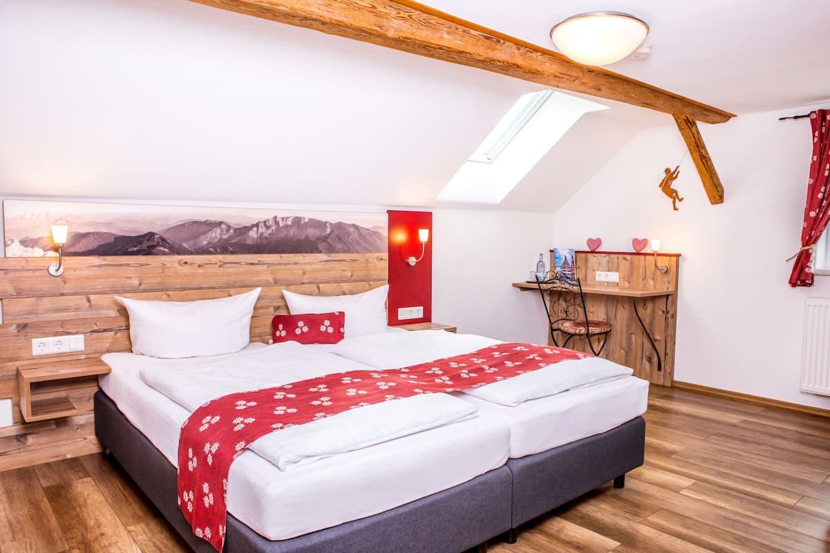 Ein Schlafzimmer mit einem großen Bett, einem Holz-Kopfteil, einem Oberlicht, einem kleinen Schreibtisch und einer roten Wanddekoration.