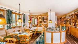 Een gezellig restaurant met houten meubels, groen-wit geruit tafelkleed en hangende吊灯.