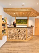 Una recepción con encimera de madera y una exhibición en la pared que muestra 'bayrischer Hof' y 'TRADITIONS-GASTHAUS'.