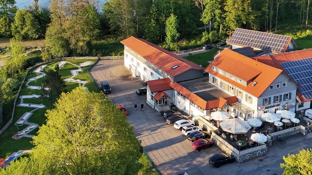Een hotel met een parkeerplaats, zonnepanelen en uitzicht op een meer.