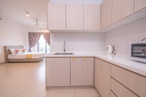 A modern kitchen with light wood cabinets, a built-in microwave, and a sink.