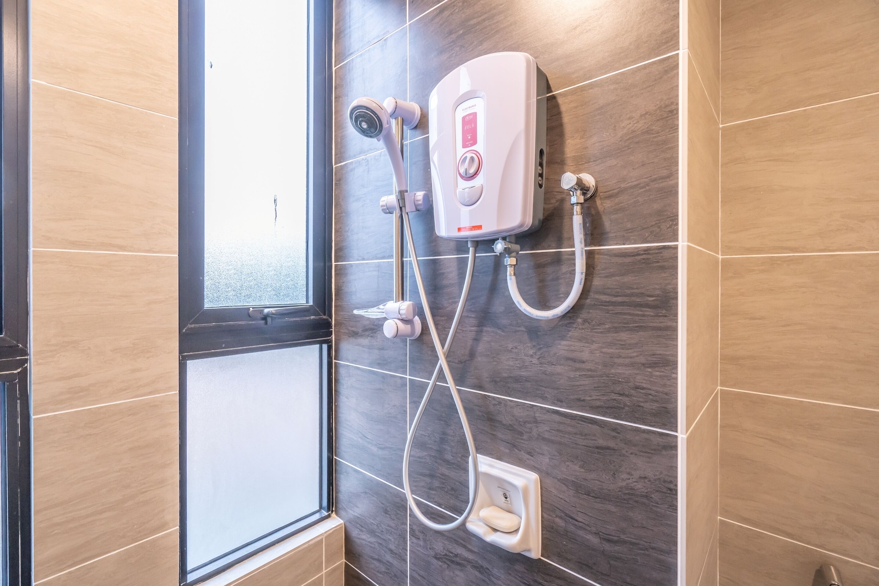 A modern bathroom with a shower unit, a window, and a tiled wall.