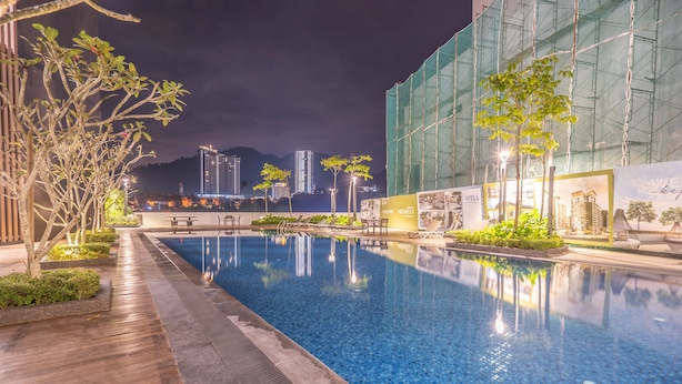 A swimming pool with a wooden deck and plants, surrounded by a building with scaffolding. - OYOHome 89448 Extraordinary Studio (Genting Highlands)