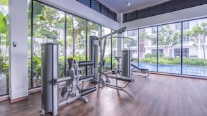 A gym with large windows, exercise equipment, and a view of a swimming pool and greenery. - OYOHome 89448 Extraordinary Studio (Genting Highlands)