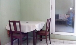 A dining area with a table and two chairs, a door, and a view through a glass door. - Apartment F2 secure city center (Antisiranana)