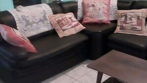 A living room with a black leather sofa, a small coffee table, and decorative pillows. - Apartment F2 secure city center (Antisiranana)