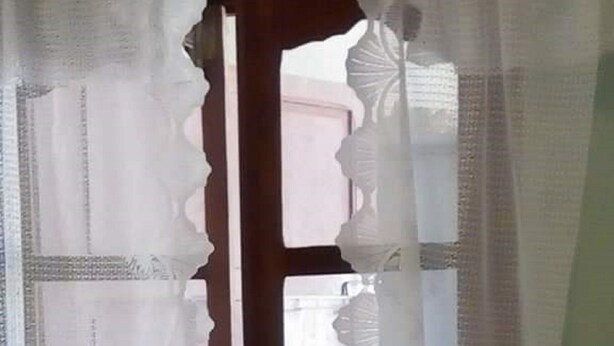 A room with a wooden door and a window with a decorative curtain. - Apartment F2 secure city center (Antisiranana)