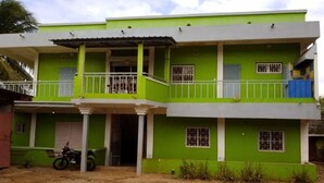 A two-story building with a green facade, white balconies, and barred windows. - Apartment F2 secure city center (Antisiranana)
