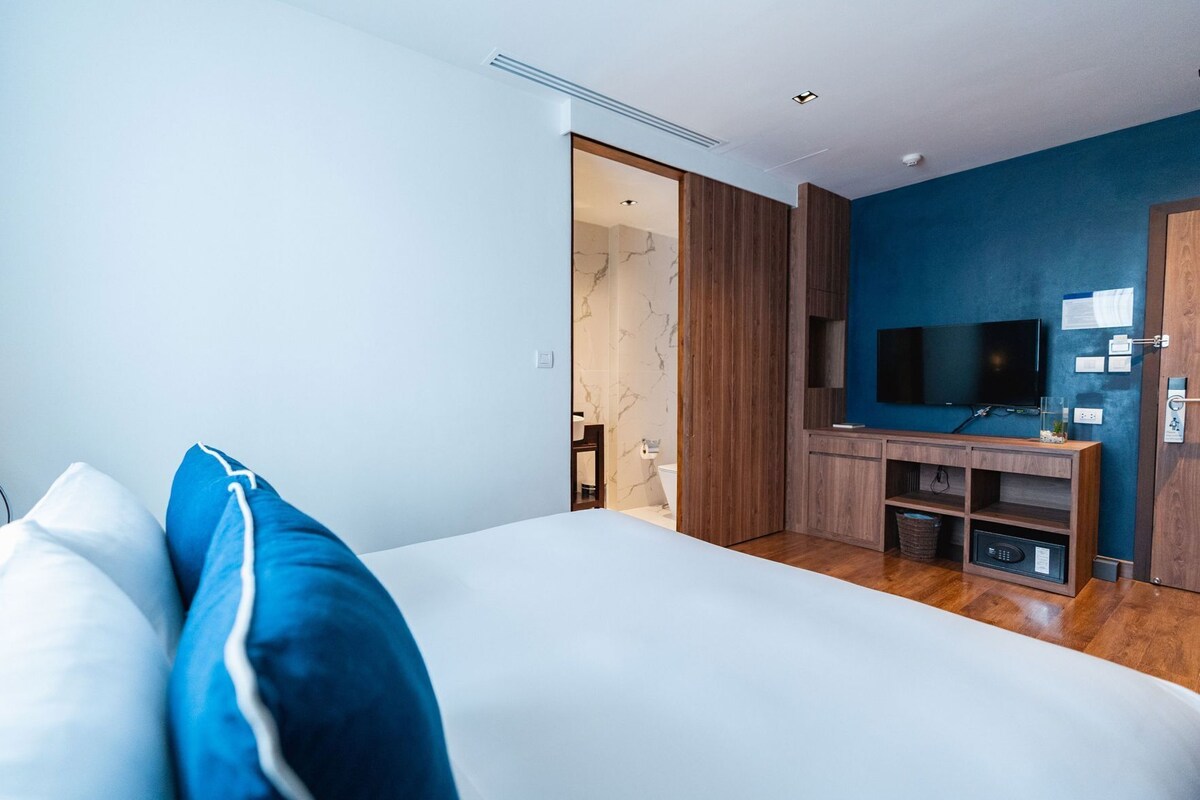 Une chambre d’hôtel moderne avec un grand lit, une télévision et une armoire en bois.