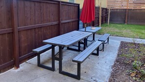 Un espace extérieur aménagé avec des tables de pique-nique et un parasol rouge.