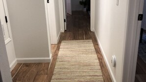 Un couloir avec un plancher en bois et un tapis beige.