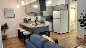 Una cocina moderna con una isla central, taburetes de bar, horno empotrado y refrigerador.