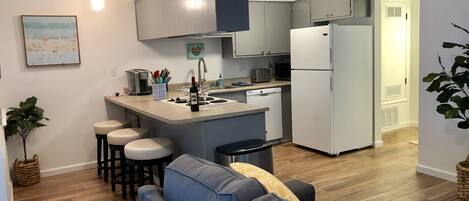 Una cocina moderna con una isla central, taburetes de bar, horno empotrado y refrigerador.