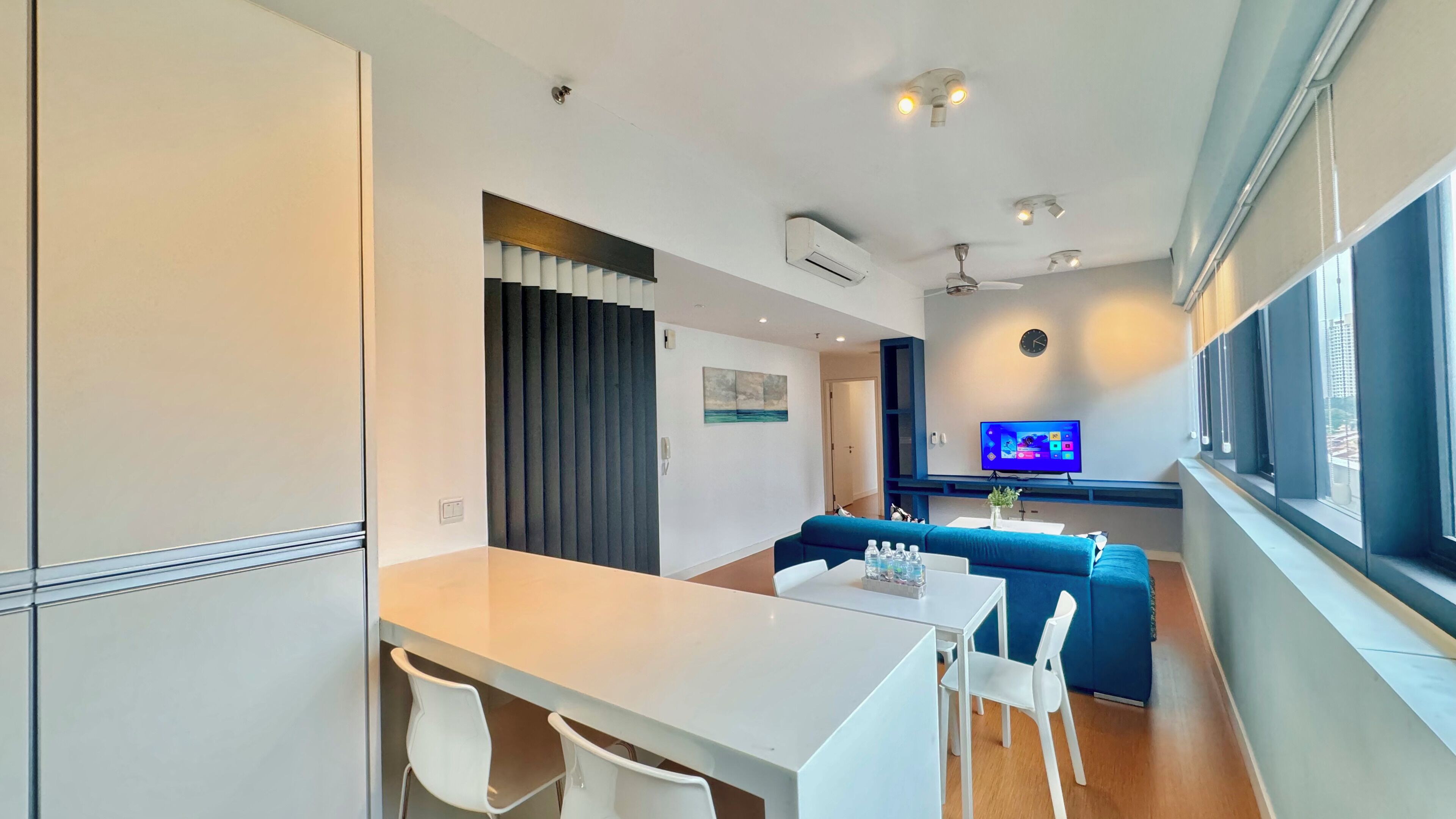 A modern living room with a sofa, a TV, and a dining area with a table and chairs.