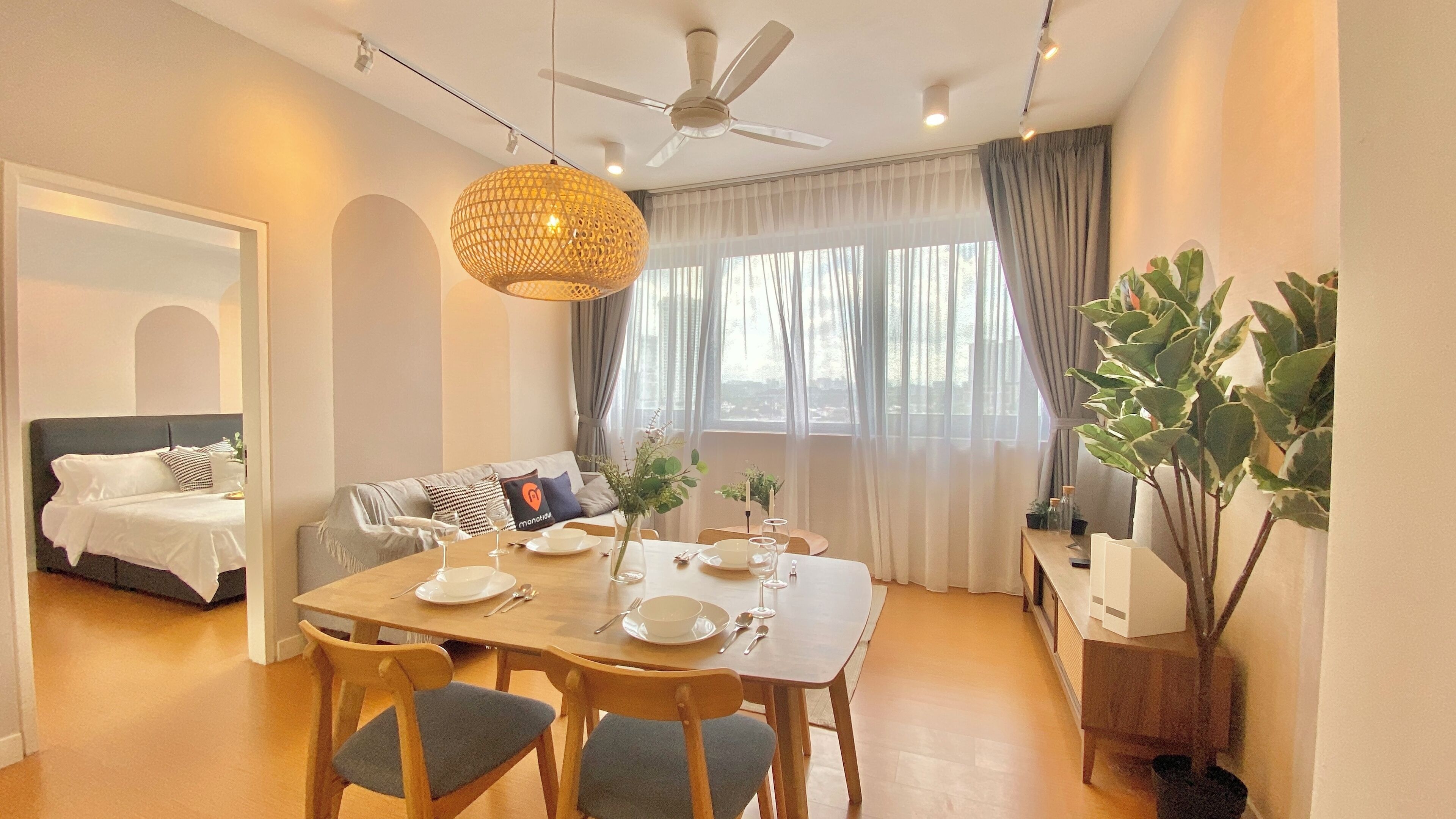A modern living room with a dining area, a sofa, a ceiling fan, and a large window with curtains.