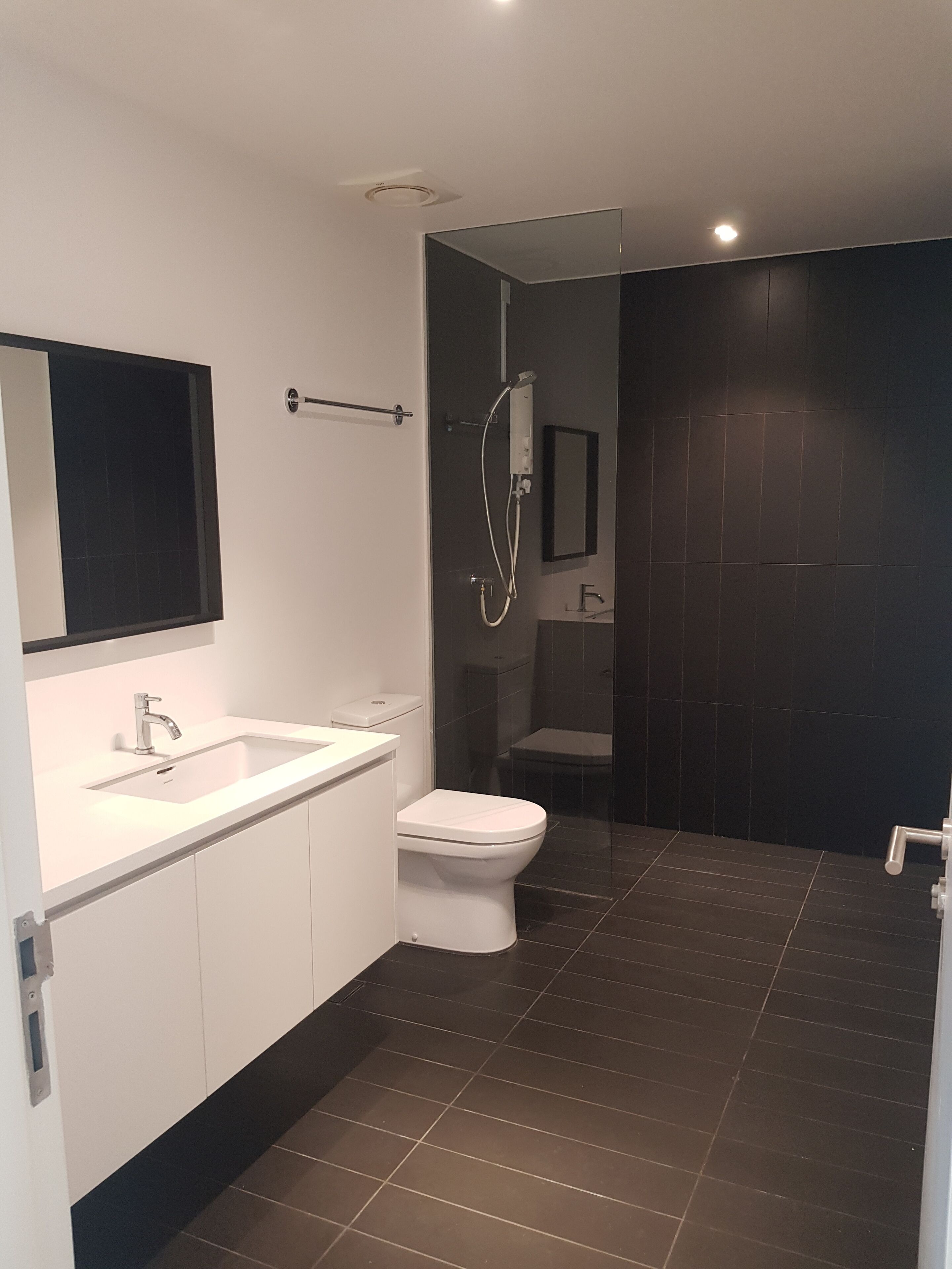 A modern bathroom with a white sink, a toilet, and a shower.