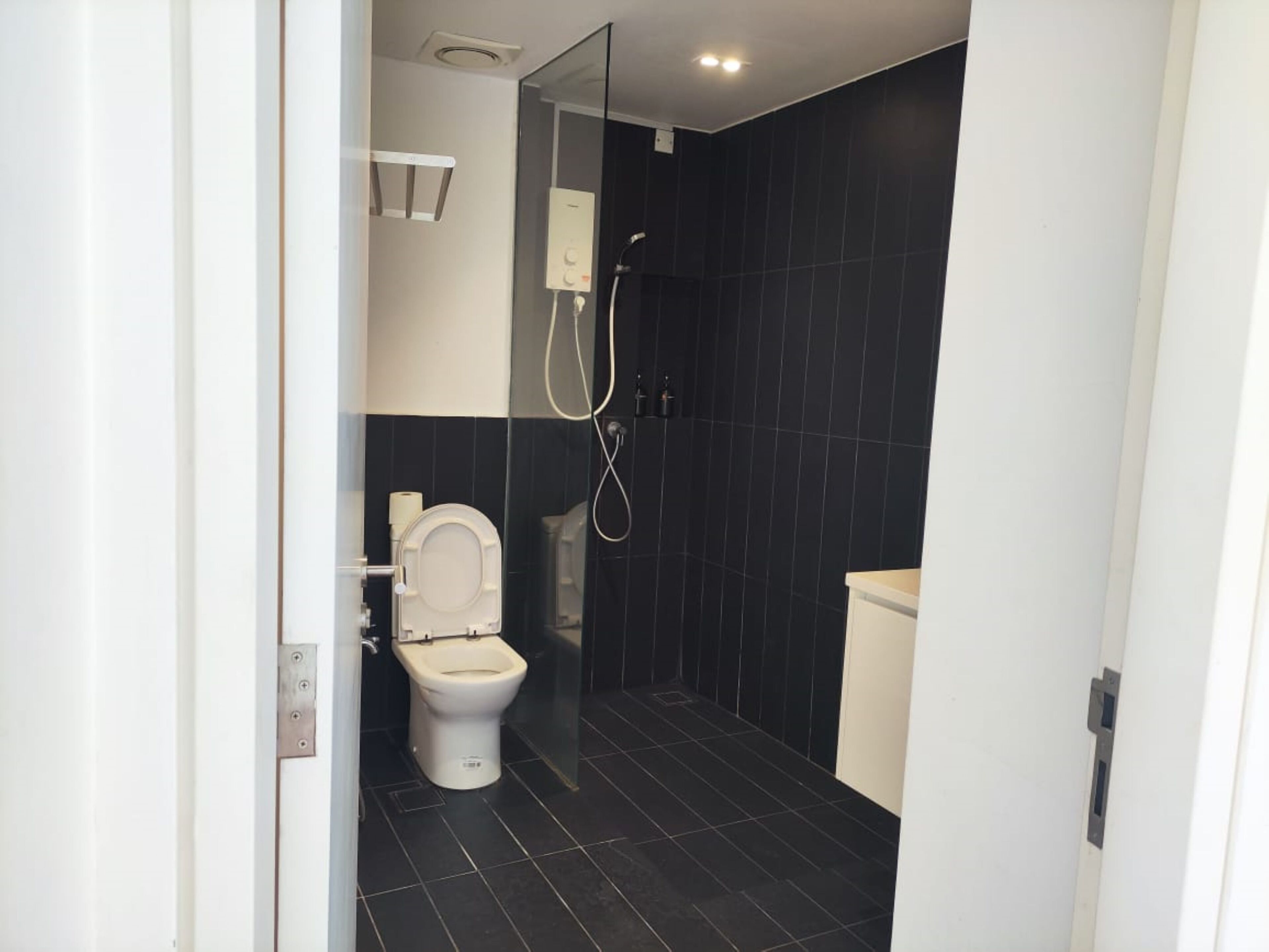 A modern bathroom with a toilet, a shower, and a sink.
