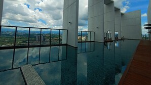 A modern infinity pool with a clear view of the cityscape and mountains in the background.