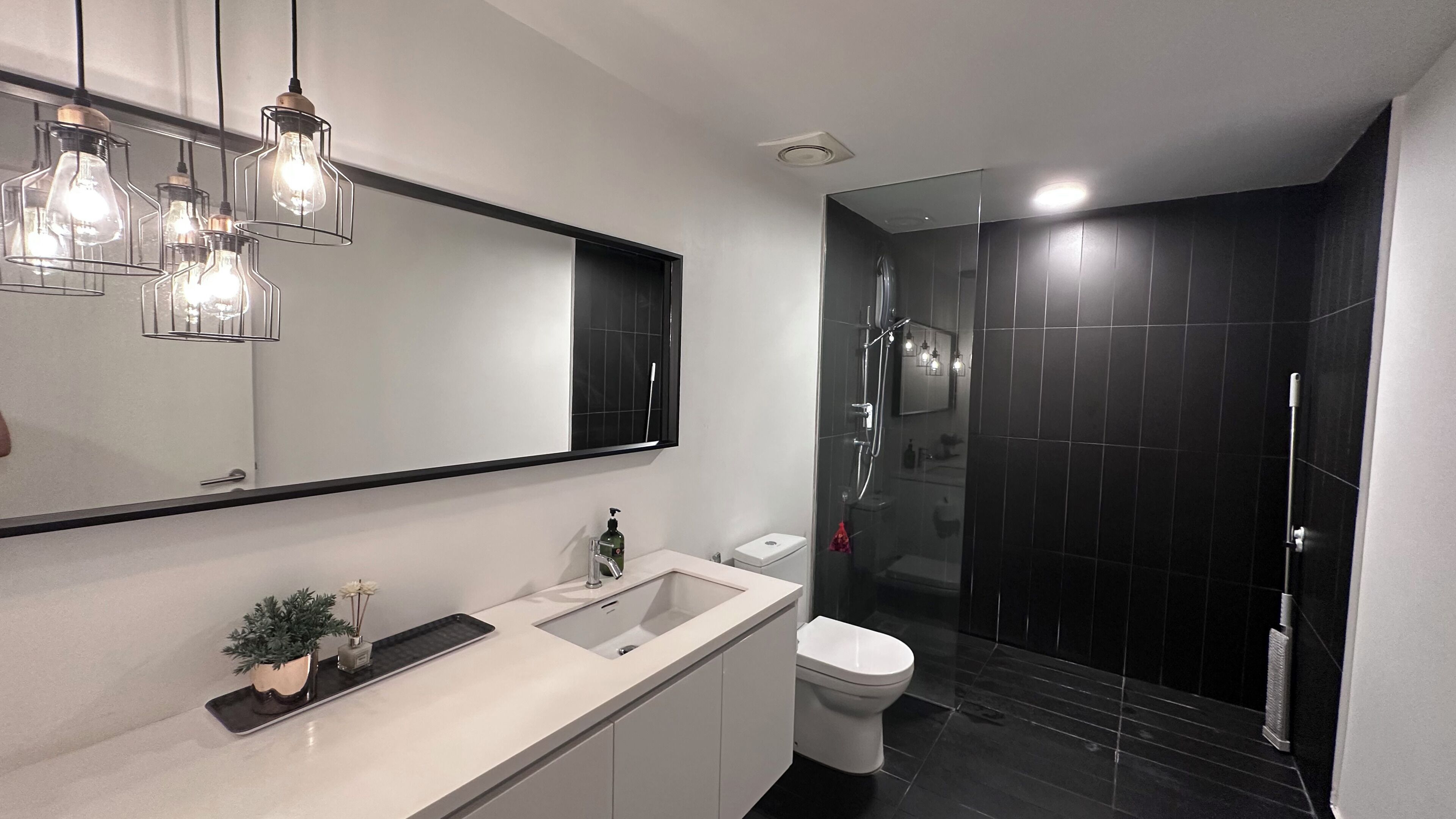 Ein modernes Badezimmer mit großem Spiegel, Waschbecken, Toilette und Duschbereich.