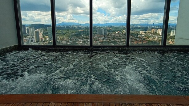 A room with a large window overlooking a cityscape with mountains in the distance.