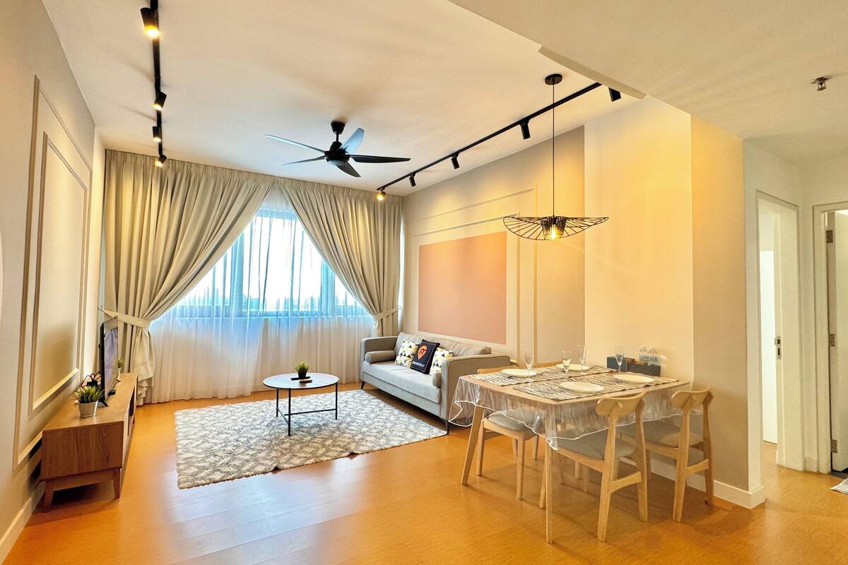 Un salon moderne avec un canapé, une table à manger pour deux personnes, un ventilateur de plafond et une grande fenêtre avec des rideaux.