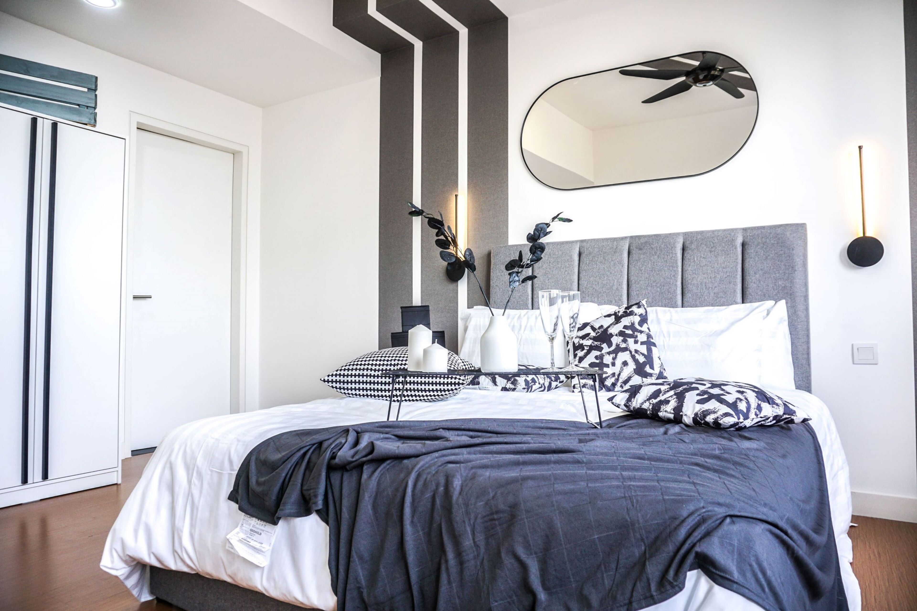 A modern bedroom with a bed, bedside table, and a ceiling fan.