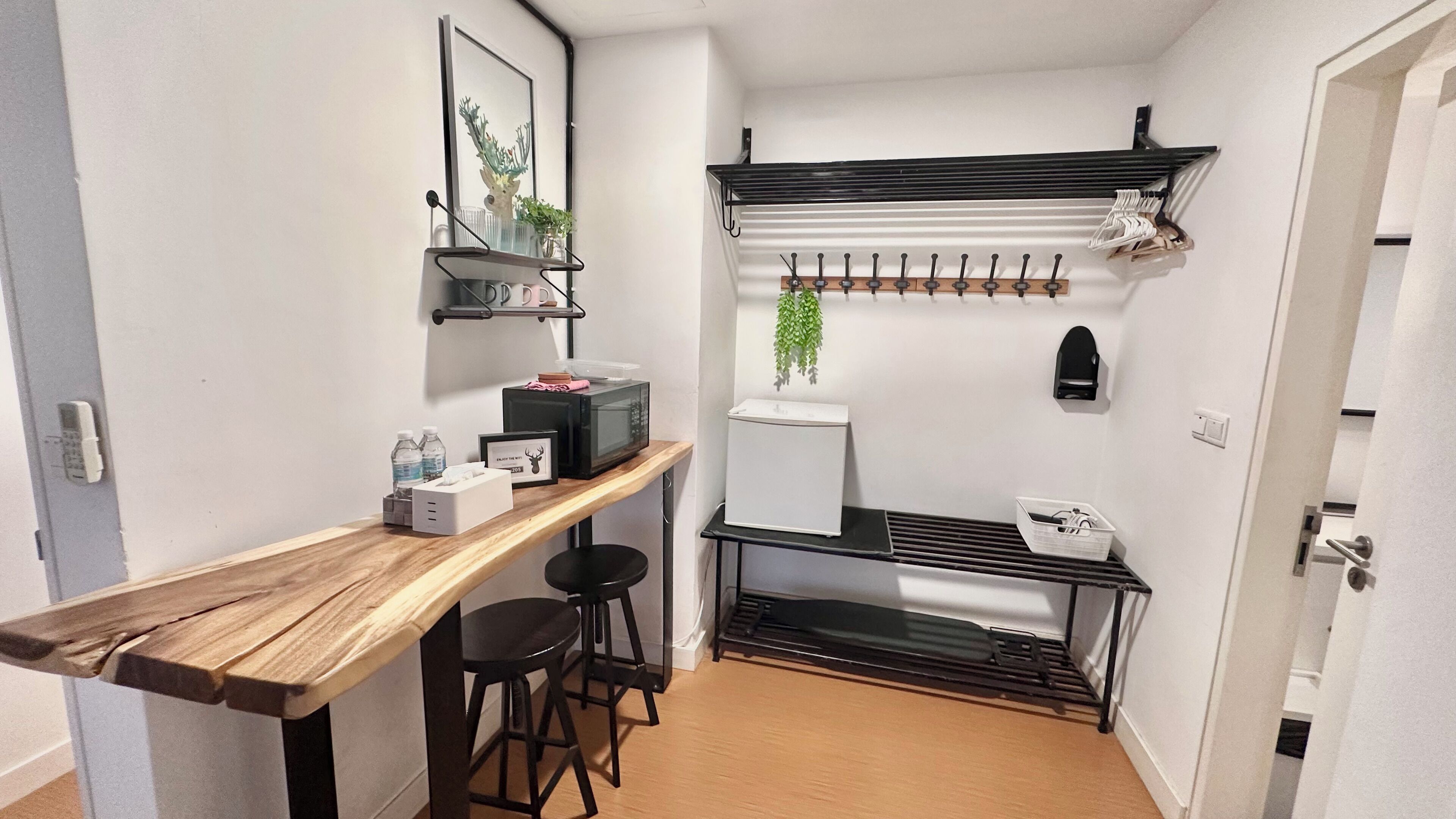 A compact kitchenette with a wooden countertop, a microwave, a refrigerator, and a hanging plant.
