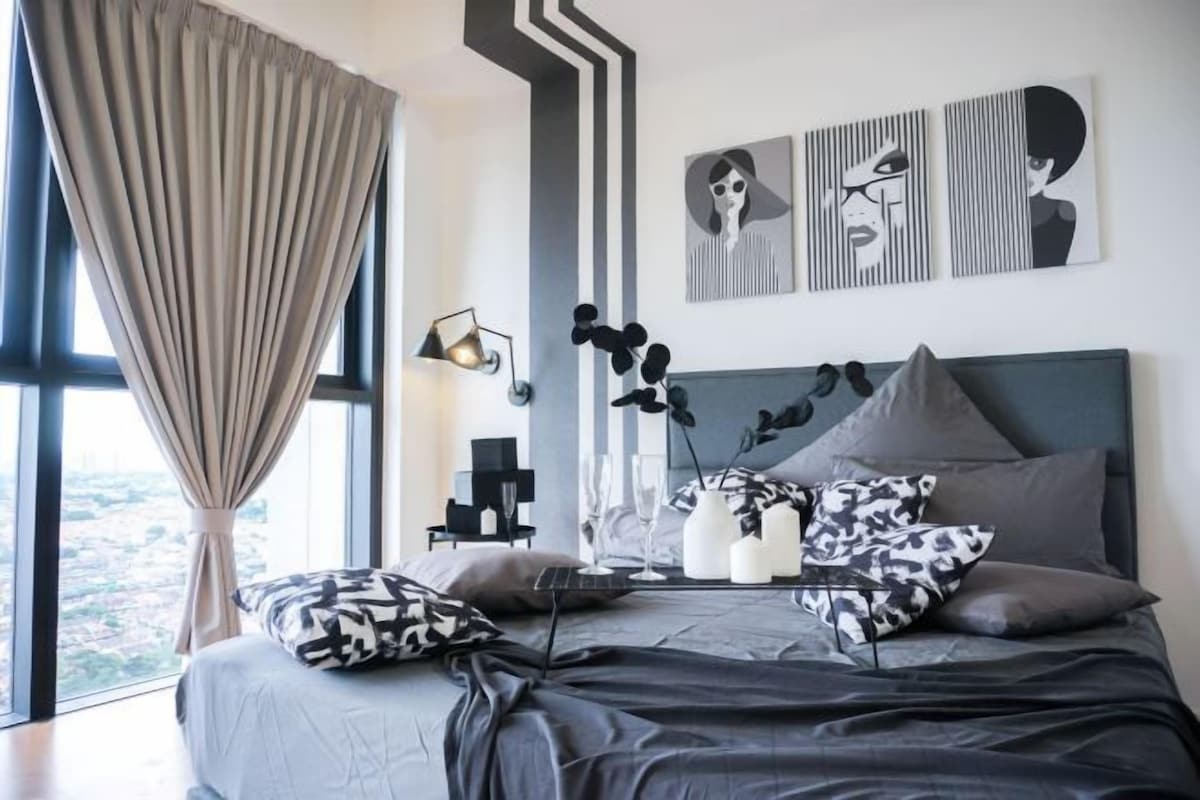 Una camera da letto moderna con un letto grande, vista sulla città e opere d'arte astratte alle pareti.
