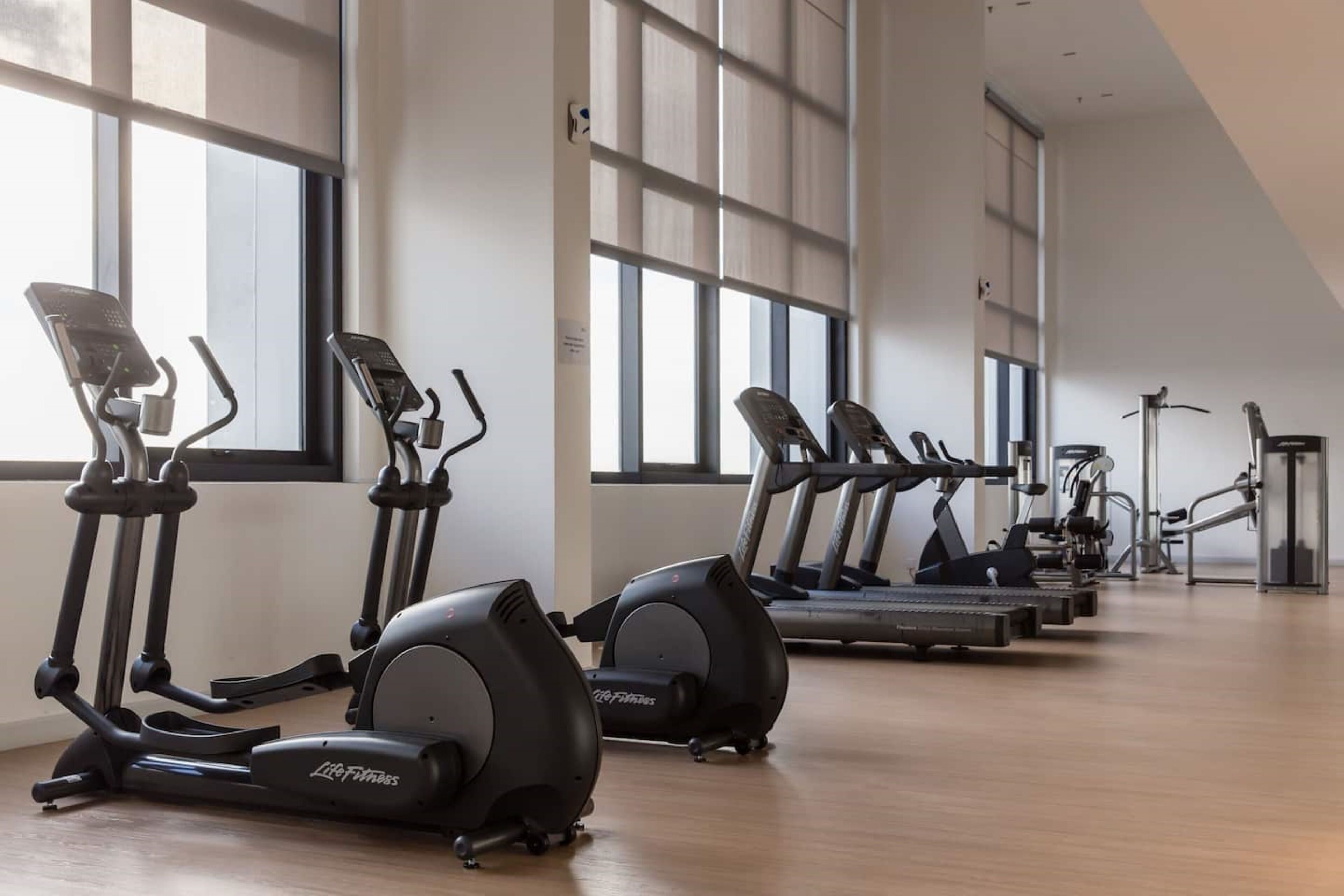A gym with various exercise equipment including treadmills, elliptical machines, and stationary bikes.