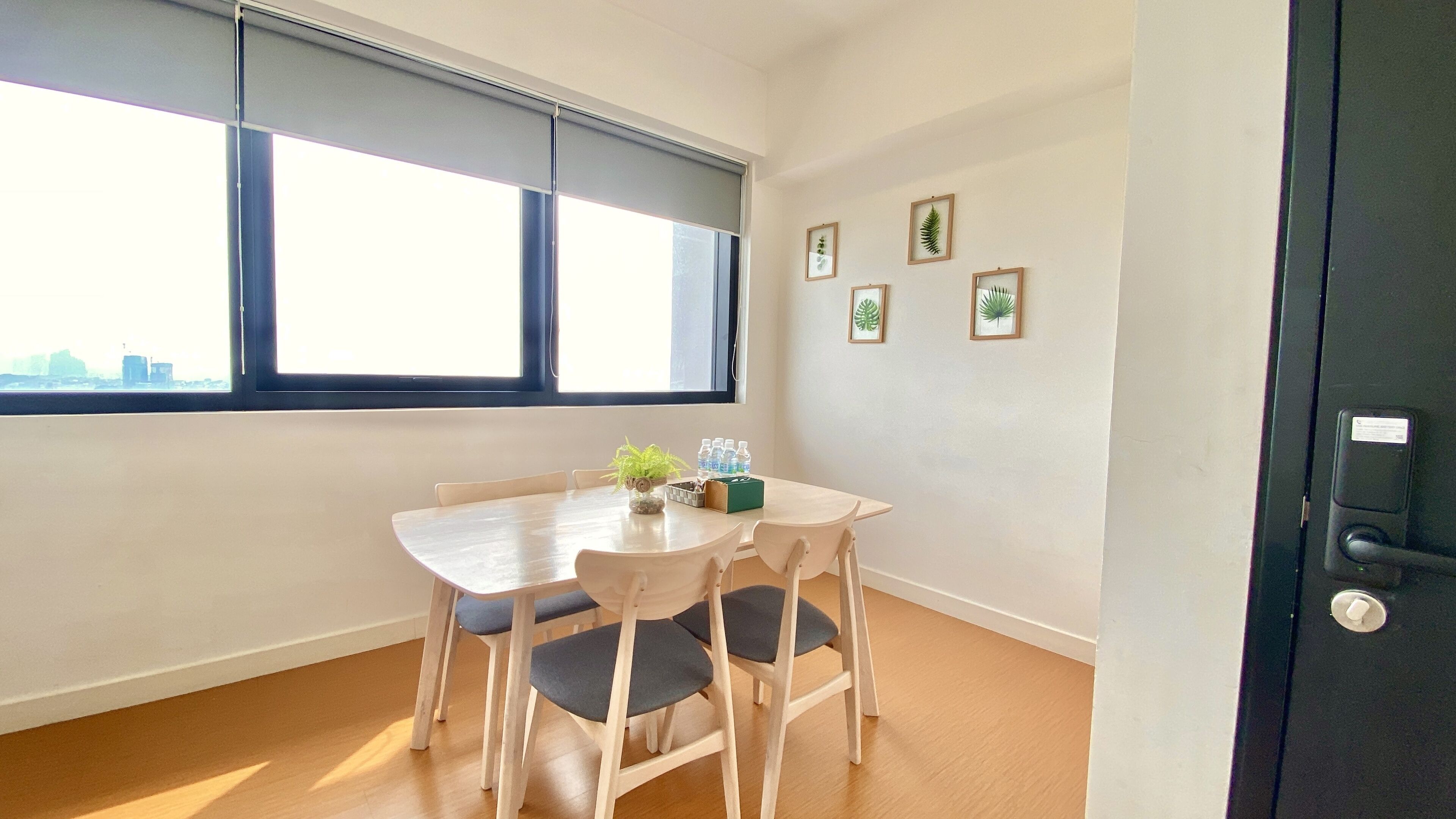 A room with a wooden table and chairs, a window with blinds, and a door with a lock.