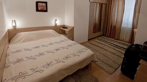 A hotel room with a bed, bedside table, lamp, and a view of the outside through the window. - Dorobanti 11 - 2 bedroom apartment (Sector 1)