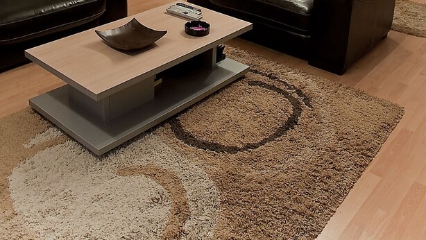 A modern living room with two black leather sofas, a wooden coffee table, and a large rug. A kitchen with stainless steel appliances is visible in the background. - Dorobanti 11 - 2 bedroom apartment (Sector 1)
