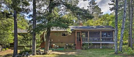 Une cabane dotée d’une véranda, entourée d’arbres.