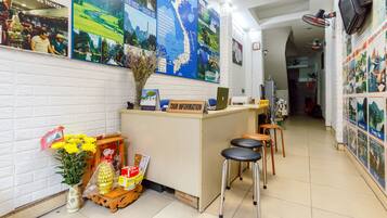 A reception area with a desk, two stools, a map on the wall, and a vase with flowers.