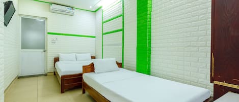 A room with two beds, a radiator, an air conditioning unit, and a door.